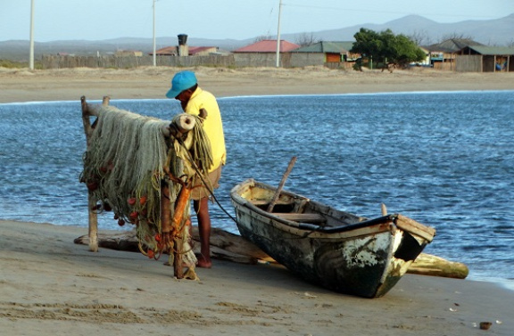 Halász bíbelődik a hálójával az érdektelen tengerparton