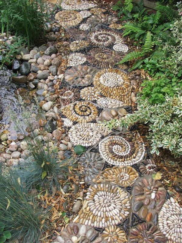 looks like they made smaller stepping stones with the designs and then placed them together and filled it in Love It!