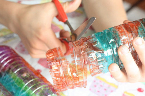 A child cutting a coloured water bottle.